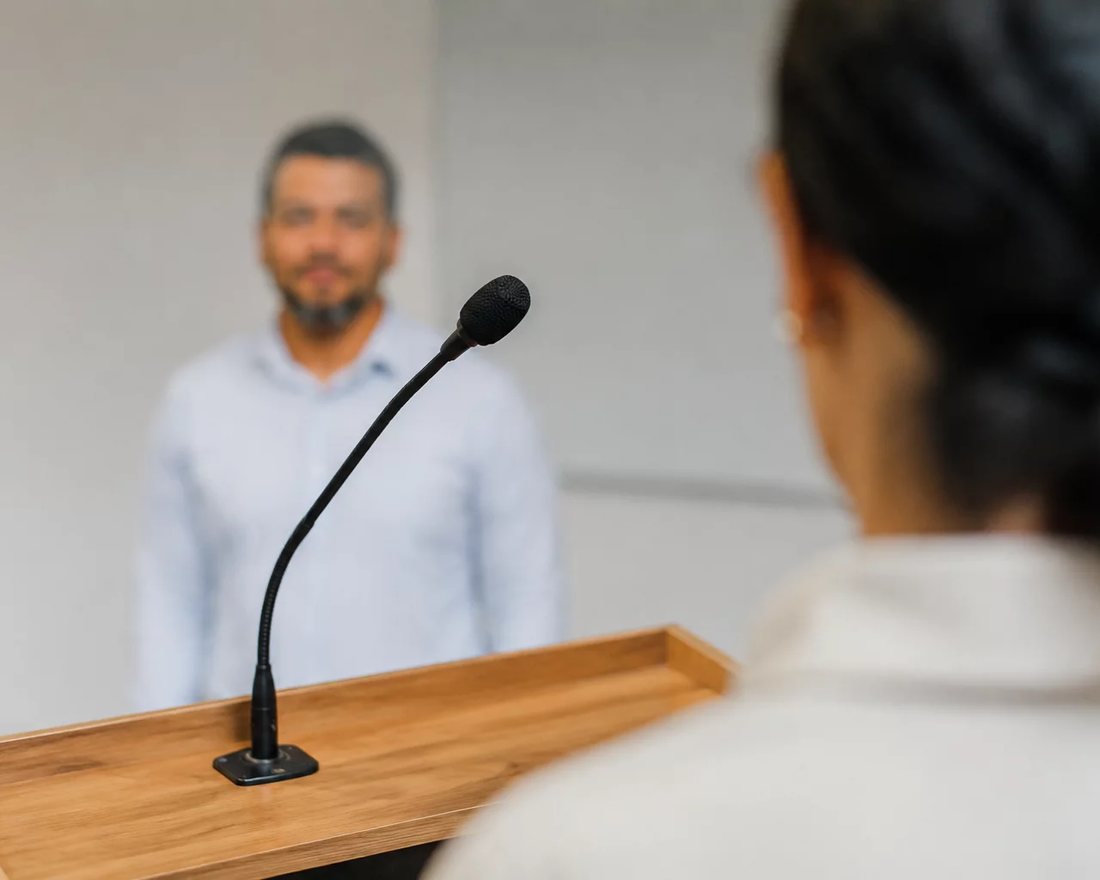 Participante ergue a mão para pedir a palavra numa mesa coberta de folhas anotadas